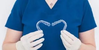 Dental tech holding a set of Spark Clear Aligners in a heart pattern