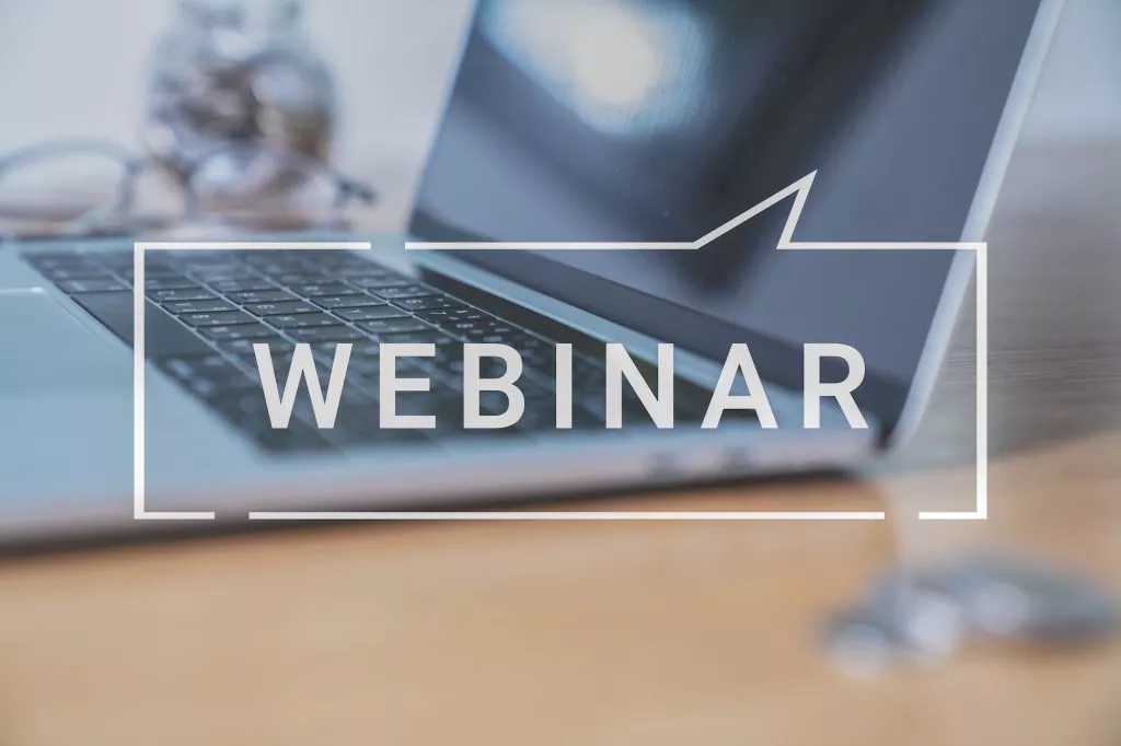 Laptop open with the Word Webinar over laying the image